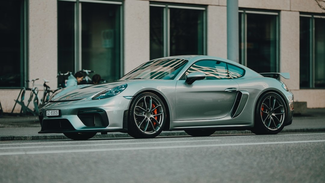 Silver sports car with orange brake calipers on city street.